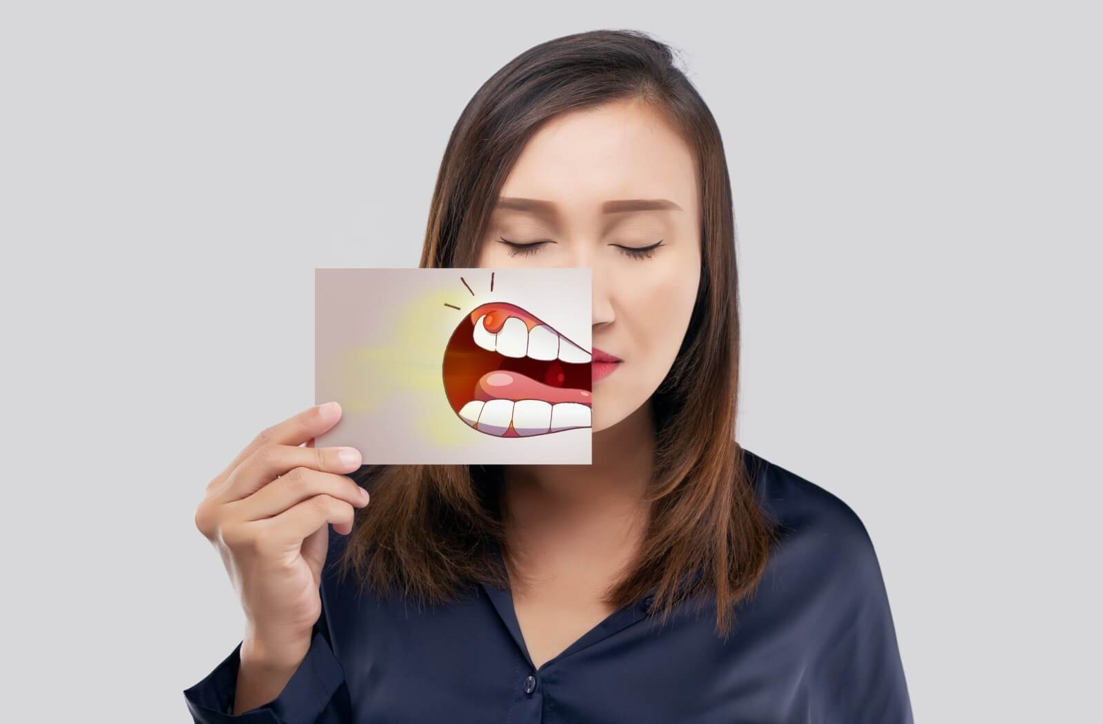 A person holds an informative illustration that shows where dental abscesses can form and what they look like.
