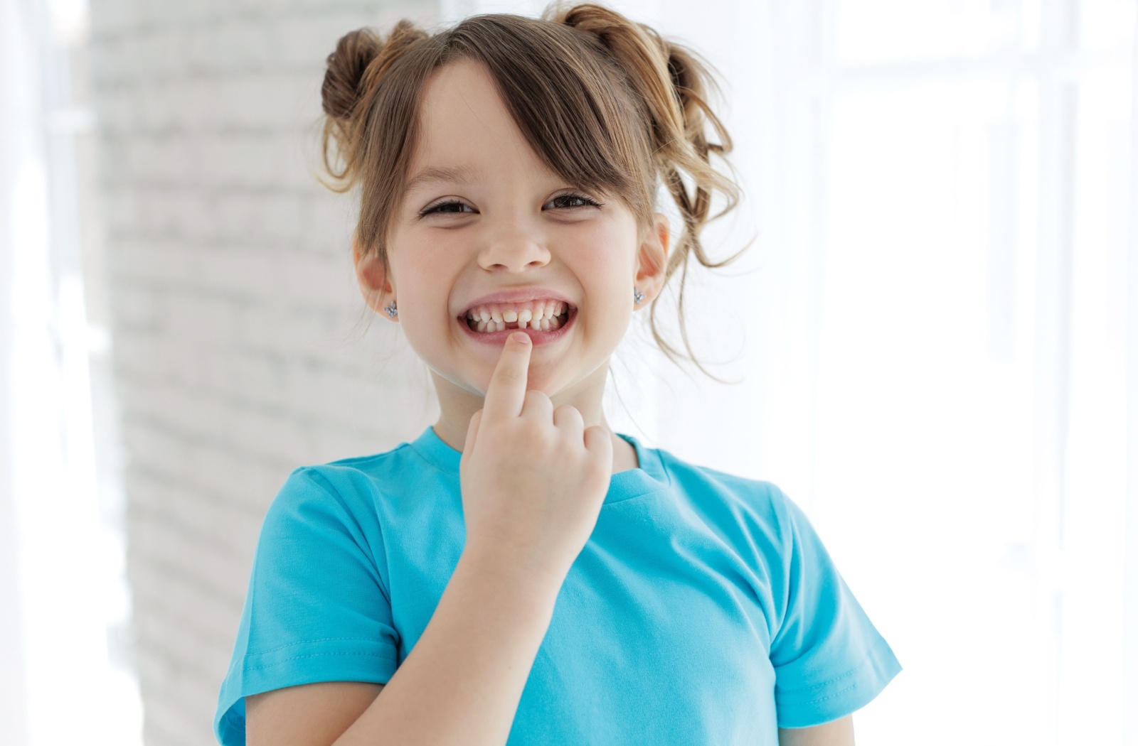 A child smiling pointing to the gap where a tooth has fallen out.